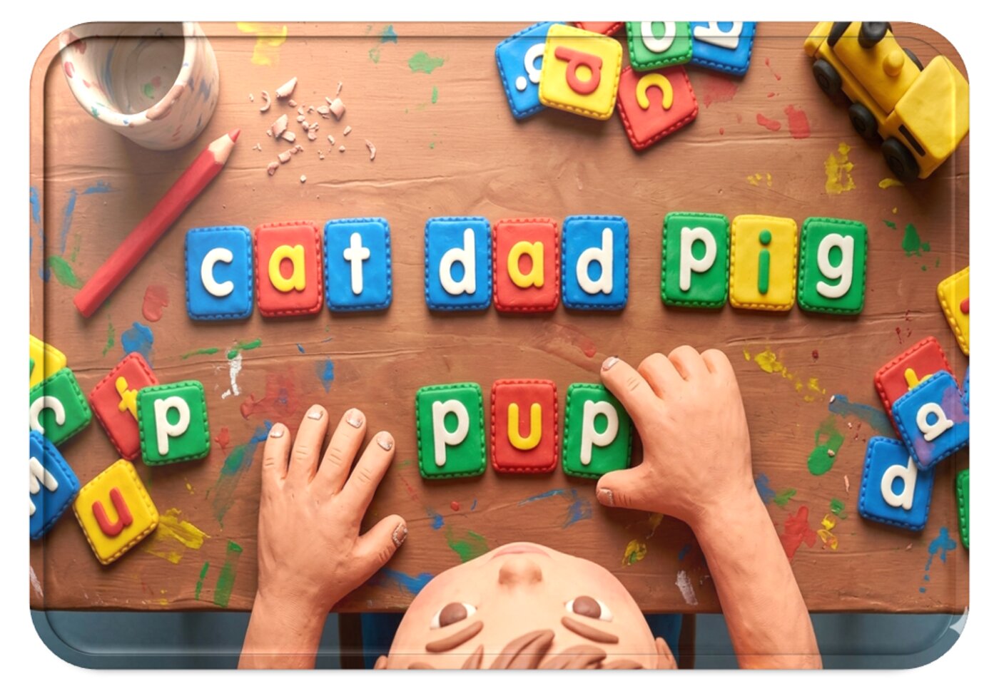 A child building the CVC words cat, dad, pig and pup using printable letter tiles on a table